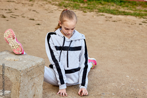 Teenager woman doing stretching exercises during a workout outdoors on a sunny summer day