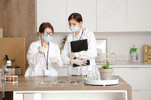 Female scientists working with plant sample at table in laboratory