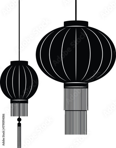 Two traditional black chinese lanterns with tassels hanging against a white background