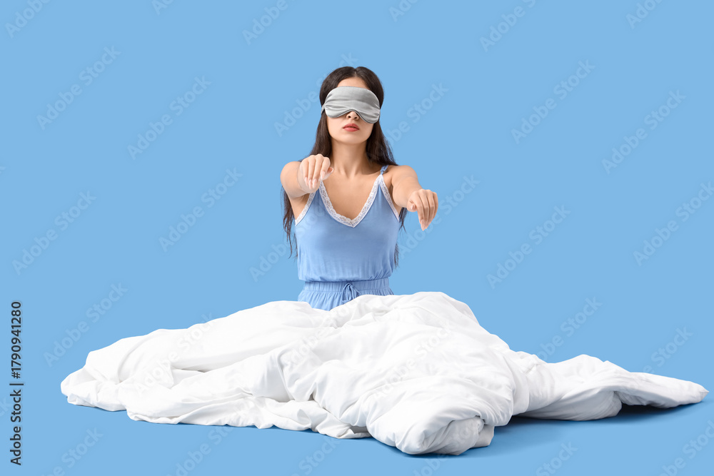 Naklejka premium Female sleepwalker in pajamas with blanket sitting on blue background