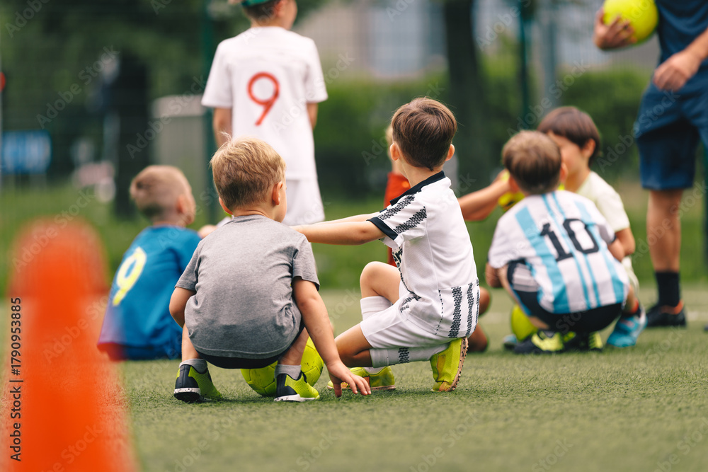 Obraz premium Kids Soccer Training – Young Children Sitting on Field During Football Practice. Youth Team Sports, Learning and Teamwork