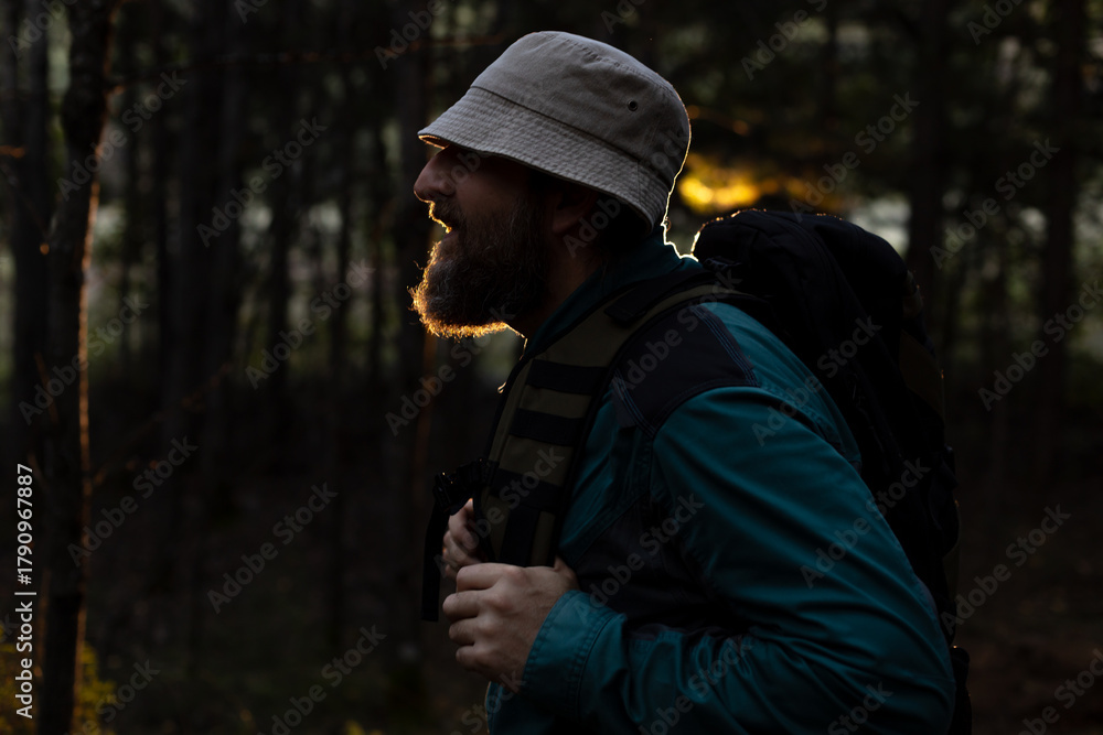 Obraz premium A man with a beard and a hat is walking through a forest