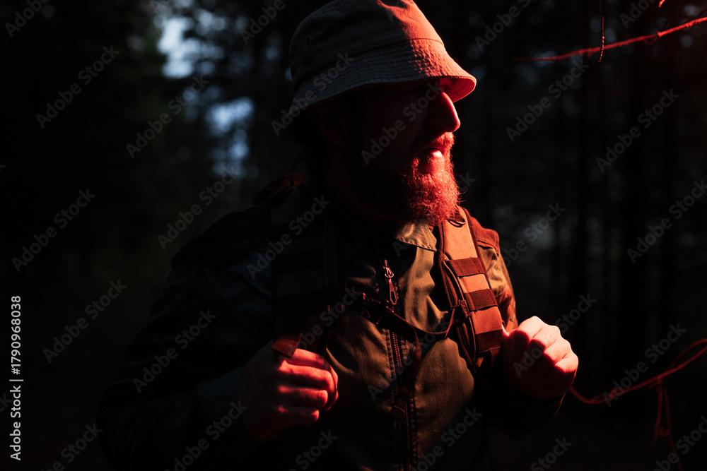 Naklejka premium A man with a beard and a hat is walking in the woods