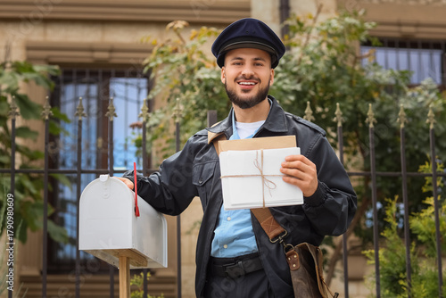 Handsome postman with lette...