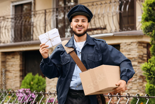 Foto Handsome postman with parcel and letters on street