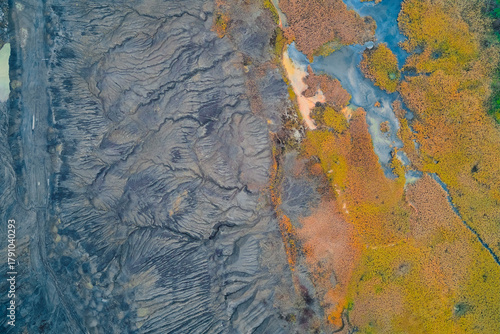 Drone aerial survey over agricultural landscape used for environmental conservation and biodiversity observation - aerial lava and marsh contrast, braided gray lava 
