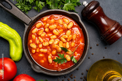 Baked bean dish in cast iron pan on black background. 