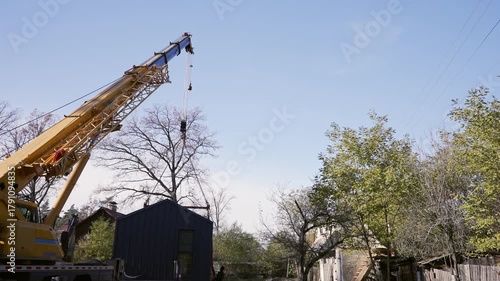 A truck crane lifts a modular house.