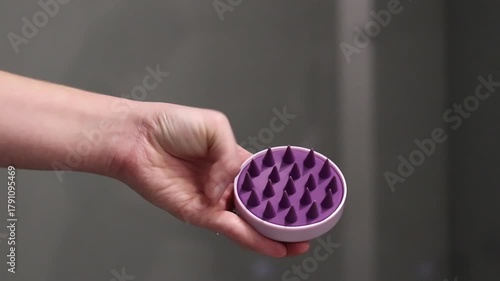 Brush for head massage and hair care. Silicone scalp massager in a woman's hand. Close-up of a girl's hand bending the bristles of a silicone brush with her fingers. Scalp massager comb. Accessory