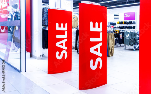 Sale signs stand at the entrance to a clothing boutique with sale information. Promotion, advertising, shopping and black friday concept