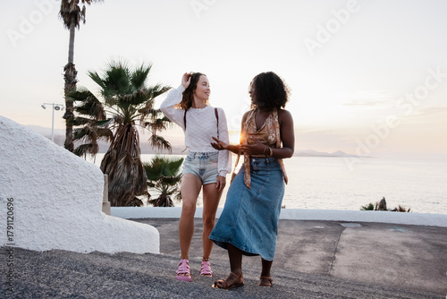 Two diverse women friends walking and talking on Canary Islands vacation