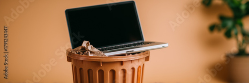 Old obsolete laptop computer discarded in a trash bin. E-waste and recycling of outdated electronic devices. Digital detox and technology frustration