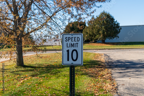 American 10 mph speed limit sign on street, white traffic sign. Horizontal photo. Classic U.S. traffic regulation sign on a street or parking area, symbol of transportation safety and traffic