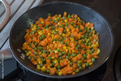 фотографія A top-down view of a black non-stick frying pan on a stovetop, containing a brig