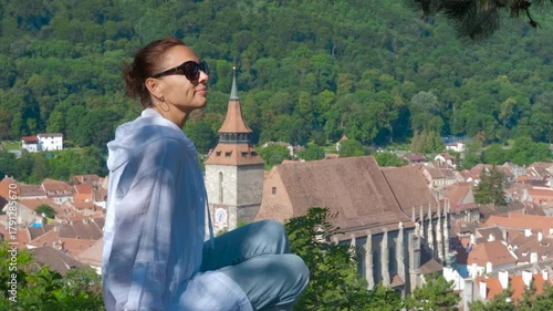 Woman enjoying the breathtaking panorama of medieval cityscape. Woman sits peacefully, admiring the stunning cityscape of Brasov, romania