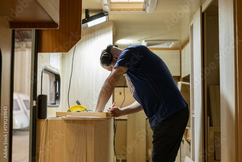 Young man renovating a caravan to convert it into a camper van