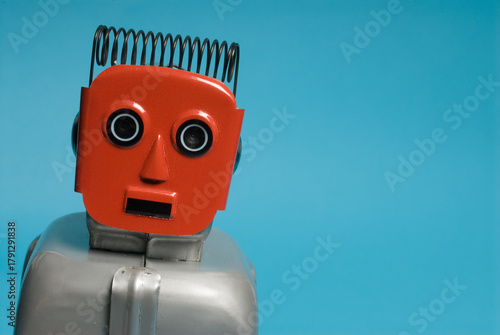 Red retro toy windup robot against blue backdrop