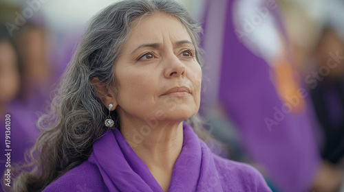 A woman in her fifties participates in a peaceful feminist protest, surrounded by the predominant color purple.