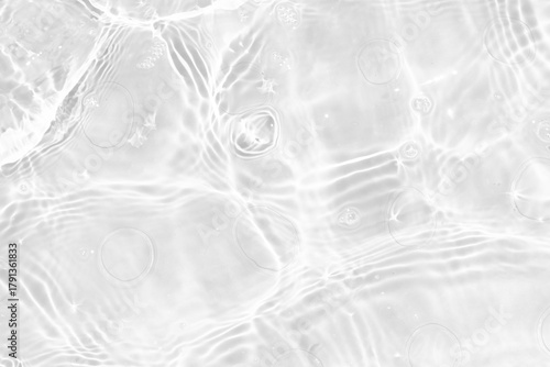 White water with ripples on the surface. Defocus blurred transparent white colored clear calm water surface texture with splashes and bubbles. Water waves with shining pattern texture background.