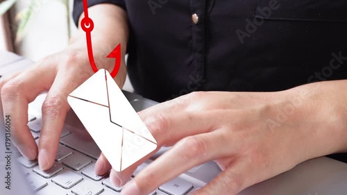 Detail of female hands typing on a laptop with an animation of a mailing envelope containing a fishhook. Phishing email
