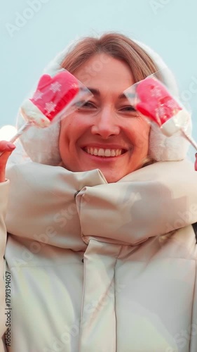 Woman wearing a cozy, fluffy coat and earmuffs smiles brightly while enjoying the festive atmosphere.