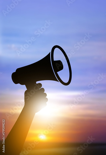 Silhouette hand holding megaphone at sunrise, voice of change and announcement concept