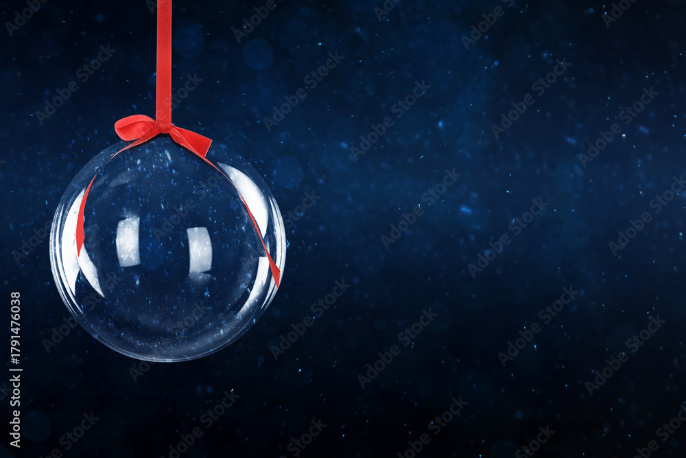 Fototapeta premium Christmas ball with red ribbon against dark background