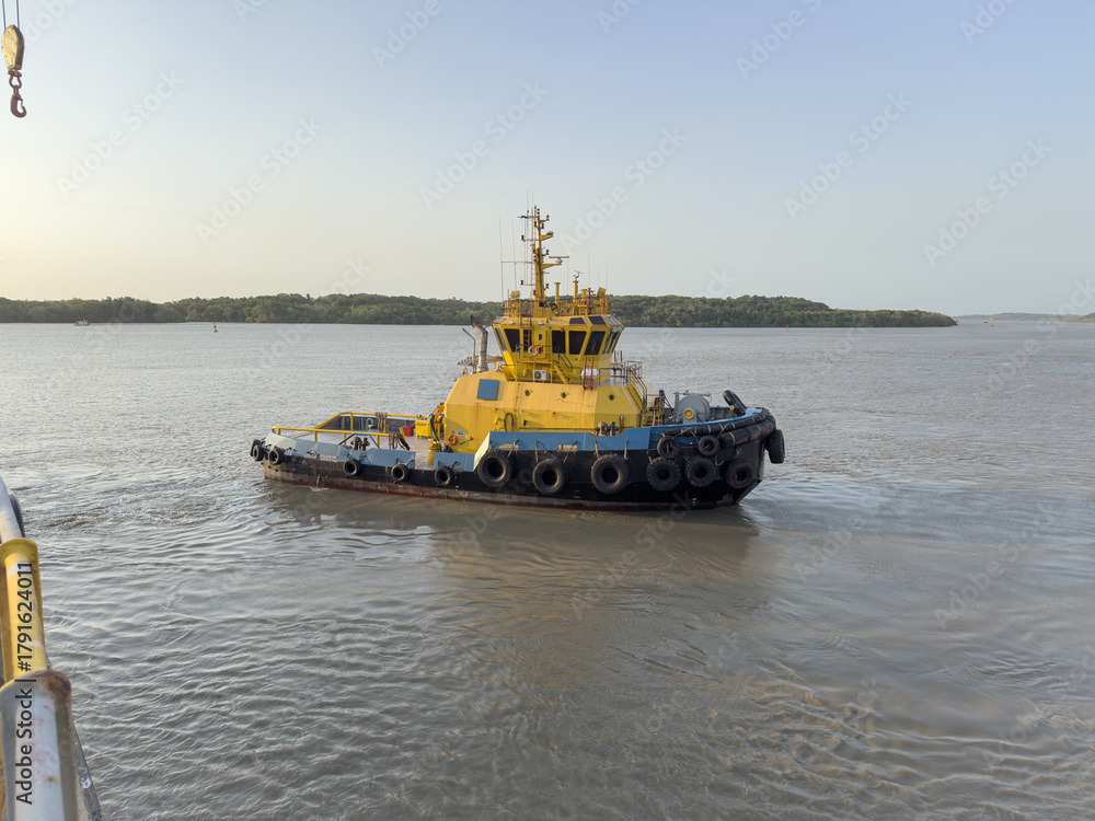 Fototapeta premium Tugboat with towline wound on winch drum assisting large vessel maneuvering during port operations. 5