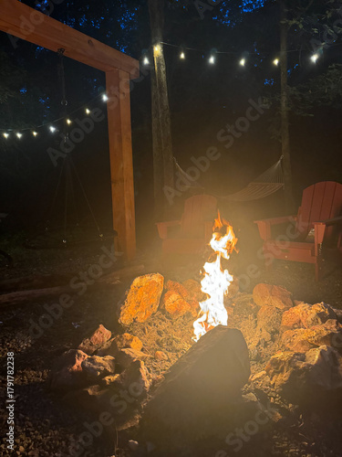 Cozy backyard fire pit with Adirondack chairs and string lights at night