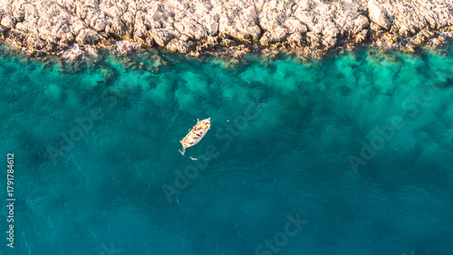 Fototapeta Naklejka Na Ścianę i Meble -  Aerial View of a Boat near the Rocky Shoreline of Kas, Turkish Mediterranean Coast