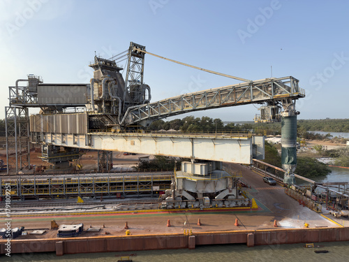 Modern port terminal unloading ore, bauxite, and petroleum coke with massive screw unloader  aluminum production. heavy machinery, cargo terminal, industrial equipment, seaport, maritime logistics 44