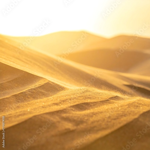 Fototapeta Naklejka Na Ścianę i Meble -  Close-up of undulating sand dunes bathed in warm, golden sunlight. Light creates texture and shadows. The scene evokes peace