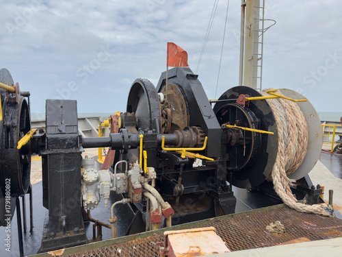 Forward mooring station of cargo ship showing windlass, mooring winches, ropes, and anchor chain. windlass