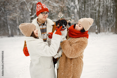 Teen siblings, their mother and black dog standing at winter park
