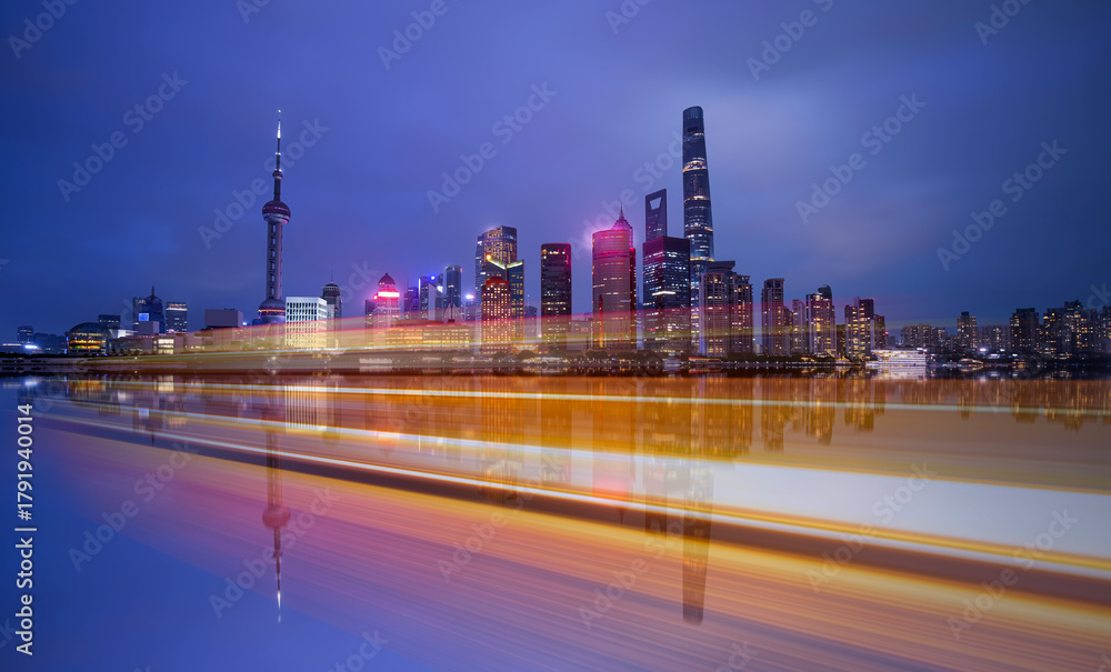 Fototapeta premium Shanghai colorful skyline with motion speed light of passing ferry in the foreground at night - Shanghai, China