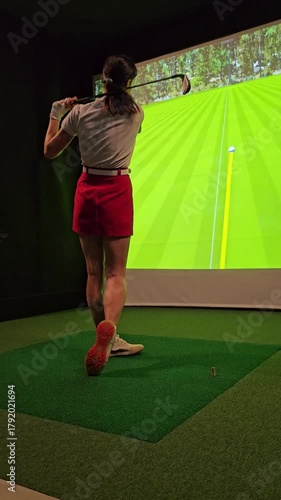 Practicing golf swing indoors with technology and virtual course simulation in modern training facility