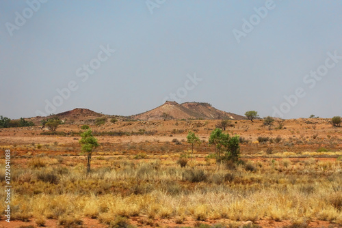 Small hills  and flat landscape in the savannah of the Northern Territory of Australia, with dry grass and small shrubs.