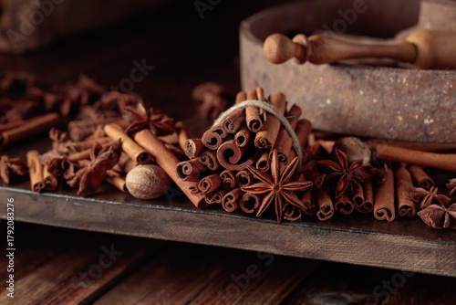 Cinnamon sticks, anise, and nutmeg on a wooden table.