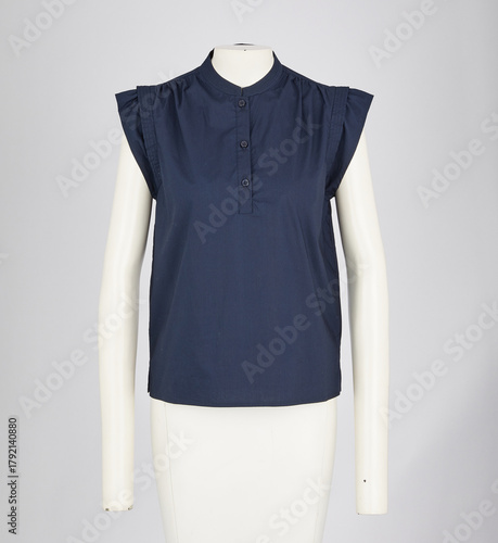 A sleeveless dark navy blue collared blouse with a button up placket displayed on a white mannequin against a plain grey background