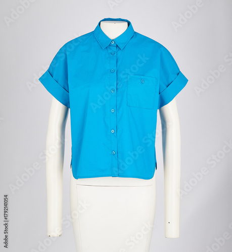 A vibrant blue short sleeved collared shirt with rolled up cuffs displayed on a white mannequin against a white background