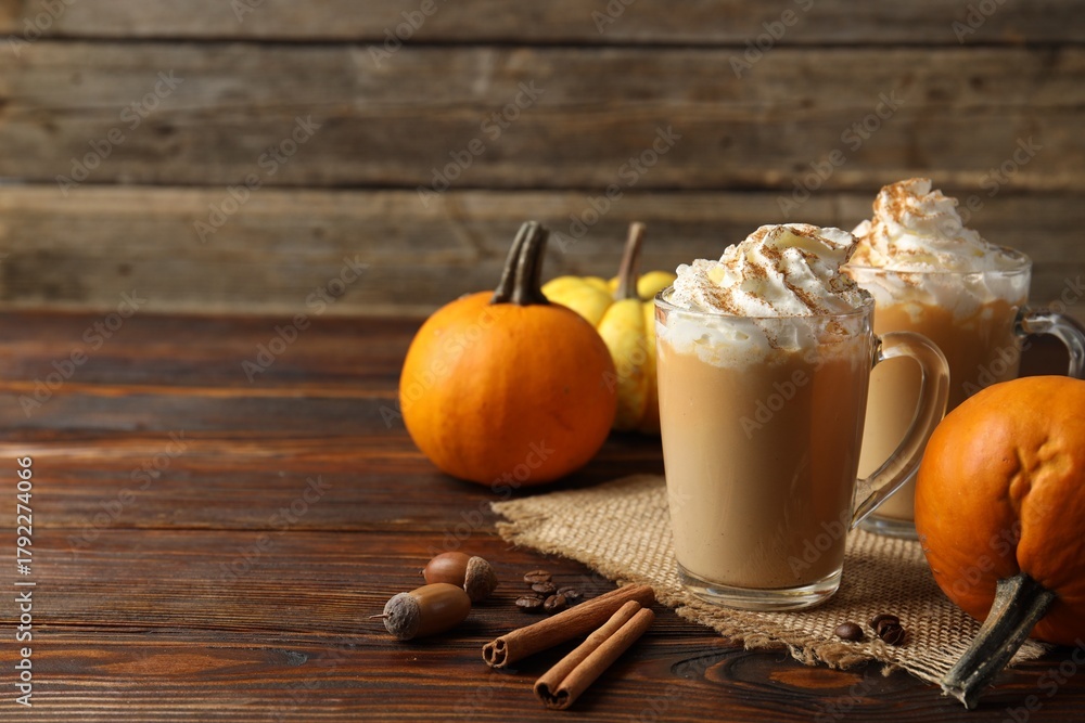 Fototapeta premium Tasty pumpkin latte with whipped cream in glass cups and ingredients on wooden table, closeup. Space for text