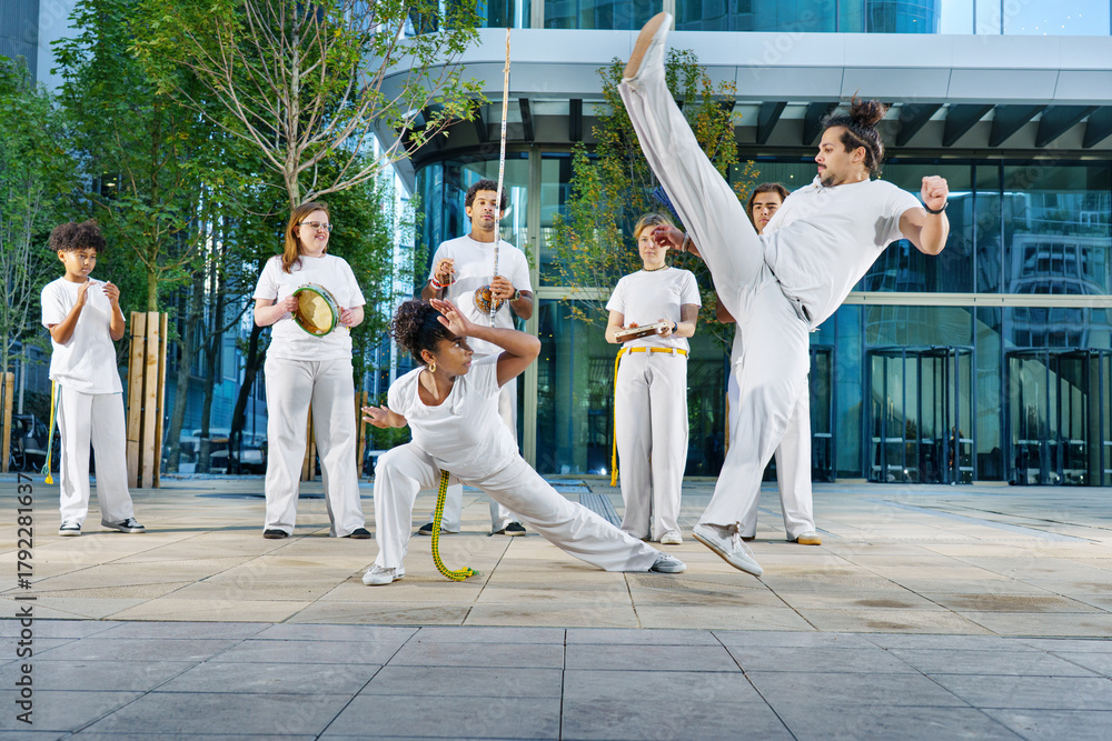 Fototapeta premium A group of sporty people of different ages training capoeira in a big city