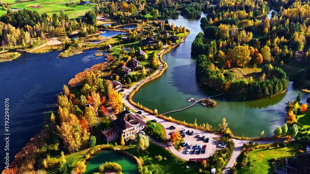 Aerial view of a picturesque village nestled among vibrant autumn forests and serene lakes, with winding roads and cozy homes.