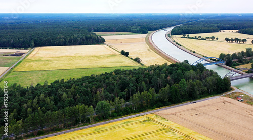 Aerial view showing agricultural fields, forests, an aqueduct bridge, and a navigable canal with a barge