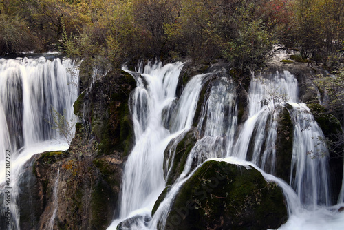 waterfall on the rocks with bushes in the park