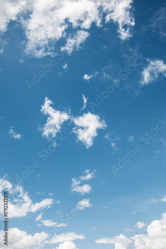 the sky is clear blue with fluffy white clouds, the sky is very bright, and the sun shines.