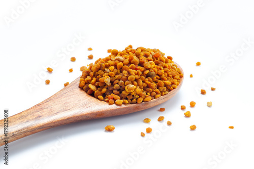 bee pollen grains in wooden spoon isolated on white background