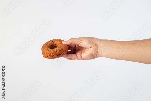 Chocolate round donut in hand on white background