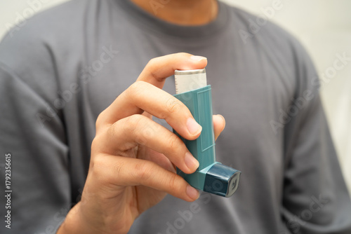 Asthma and chronic obstructive pulmonary disease COPD, Asian young man using metered dose inhaler MDI.