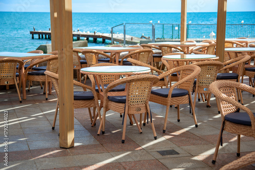 Wicker tables and chairs of an outdoor cafe by the sea